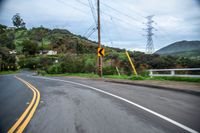 the back side of a car driving along the road near mountains and trees in the distance