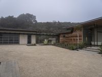 a large home with garage doors is located in the hillside area of the property with rocks and grasses