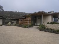 a large home with garage doors is located in the hillside area of the property with rocks and grasses