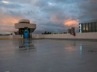 a large concrete area with a parking lot and a sky filled with clouds above it