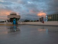 a large concrete area with a parking lot and a sky filled with clouds above it