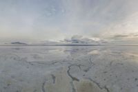 a large expanse of salt in the middle of a desert plain under a cloudy sky