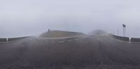 a road with several flags on top of it with fog in the air and a mountain in the background