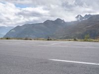 a person rides an electric skateboard across a parking space in the mountains, on an empty street and a mountain range