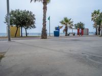 some palm trees and a parking lot by the ocean shore with colorful stalls for people to sit