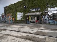 there are a lot of plants in this picture, with graffiti all over it and people walking along the street