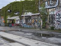 there are a lot of plants in this picture, with graffiti all over it and people walking along the street