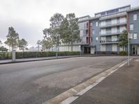 a street view with trees on either side of the road and blue buildings to the right