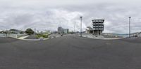 a view of the street with buildings on the side and boats in the distance, taken in a fisheye lens