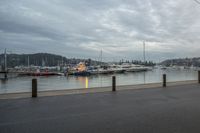 a harbor with several boats in the water and a man riding on the bike, with power lines over the water