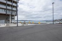 a empty parking lot next to the sea near some buildings and stairs on a beach