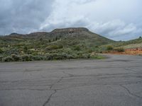 a mountain sits in the distance in a parking lot with a few trees and shrubbery