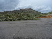 a mountain sits in the distance in a parking lot with a few trees and shrubbery