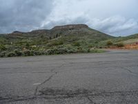 a mountain sits in the distance in a parking lot with a few trees and shrubbery