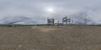 a large cell phone tower and field near water with mountains in the background of a panoramic photo