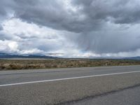 the road and the mountains with rain clouds above it is very scenic, with no grass