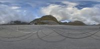 an aerial photo shows tire tracks on the ground near mountains and clouds in a blue sky