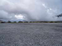 a parking lot on top of a mountain with clouds in the sky and two white cars parked near by