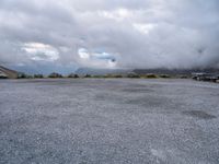 a parking lot on top of a mountain with clouds in the sky and two white cars parked near by