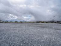 a parking lot on top of a mountain with clouds in the sky and two white cars parked near by