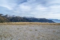 a view of some snow capped mountains and a large red fire hydrant in the field