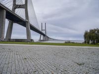 a long bridge that has a big brick walkway going under it to a field with trees in the background