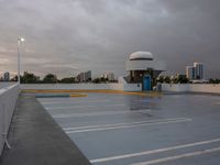 a parking lot near the water with no cars in it and a dome near the road