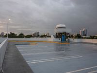 a parking lot near the water with no cars in it and a dome near the road