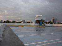 a parking lot near the water with no cars in it and a dome near the road