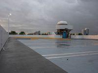 a parking lot near the water with no cars in it and a dome near the road