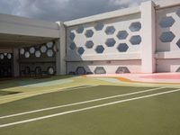 a tennis court with some chairs on the side of it and many windows in the background