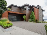 the driveway has a walkway and landscaping along it and is a brown building with three stories