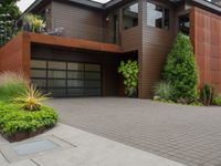 the driveway has a walkway and landscaping along it and is a brown building with three stories