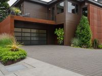 the driveway has a walkway and landscaping along it and is a brown building with three stories