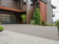 the driveway has a walkway and landscaping along it and is a brown building with three stories