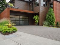 the driveway has a walkway and landscaping along it and is a brown building with three stories