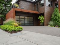 the driveway has a walkway and landscaping along it and is a brown building with three stories