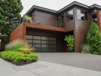 the driveway has a walkway and landscaping along it and is a brown building with three stories