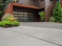 the driveway has a walkway and landscaping along it and is a brown building with three stories