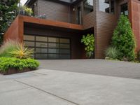 the driveway has a walkway and landscaping along it and is a brown building with three stories