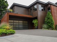 the driveway has a walkway and landscaping along it and is a brown building with three stories