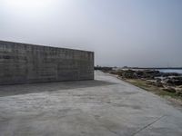 an empty concrete beach with a wall in the background on top of it next to water