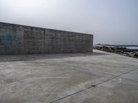 an empty concrete beach with a wall in the background on top of it next to water