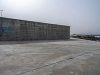 an empty concrete beach with a wall in the background on top of it next to water