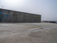 an empty concrete beach with a wall in the background on top of it next to water