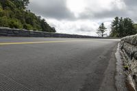 the road runs across a stone retaining wall on the side of the road, with a person on a skateboard