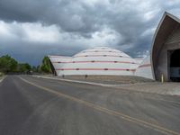 an empty street in front of a large dome like building under a grey cloudy sky