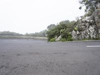 a lone bike is standing by a steep cliff face and road leading the hill,