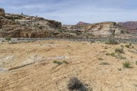 a desert with a mountain range in the background and a road running through it with no people