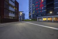 a view down an empty street in front of tall buildings at dusk at the time